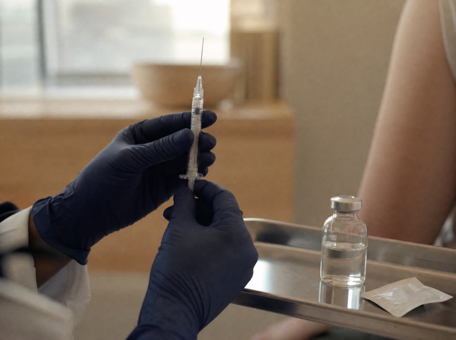 Gloved hands preparing a B-12 injection on a stainless tray