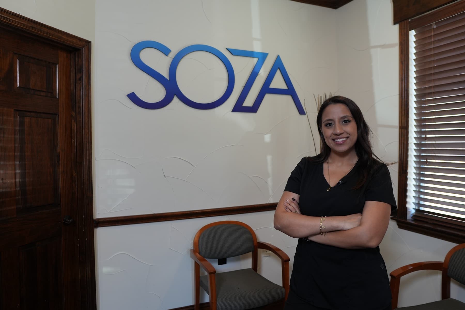 A Soza Clinic team member beside the Soza sign in the Bedford lobby